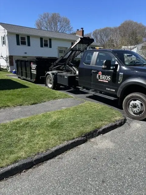 E'Bros truck dropping off a black 10 yard dumpster, dumpster rental Auburn MA