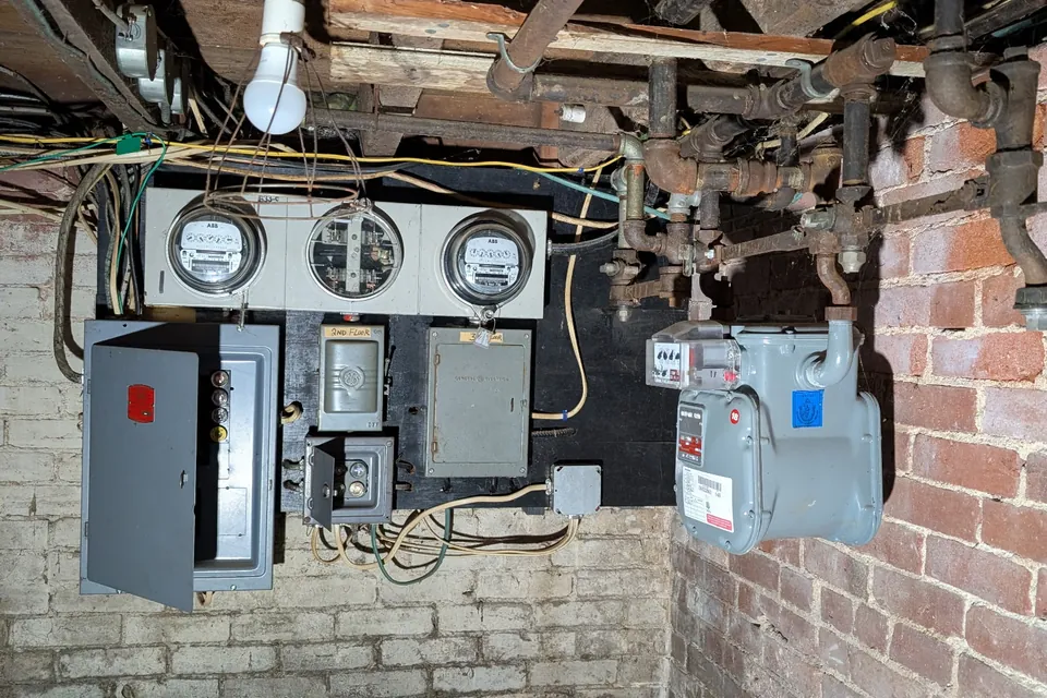 Old fuse boxes and tangled basement wiring before rebuild by Gourley Electric