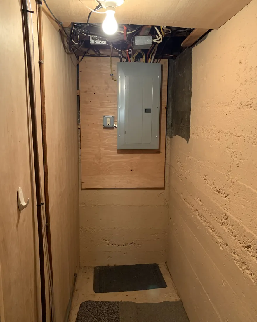 New electrical panel mounted clean on a plywood backboard in a finished basement closet by Gourley Electric