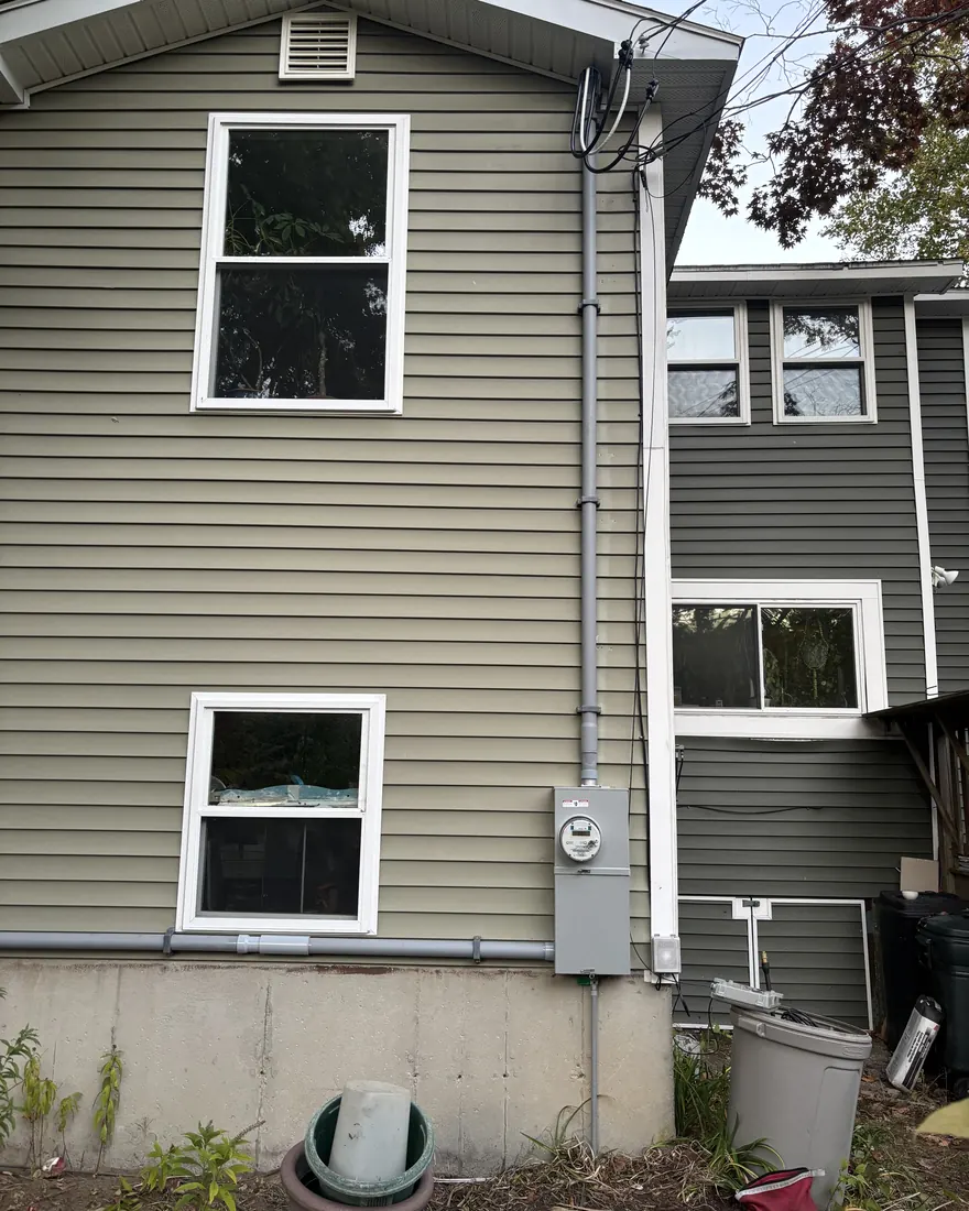New electrical service mast, riser and meter socket run clean against the siding by Gourley Electric