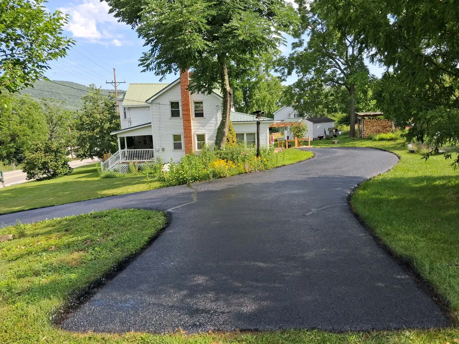 Residential sealcoating job showing curved driveway with dark asphalt sealer protecting surface