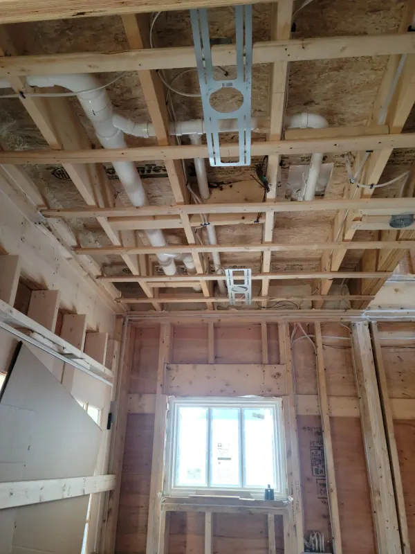 Drain lines run through ceiling joists during a rough-in